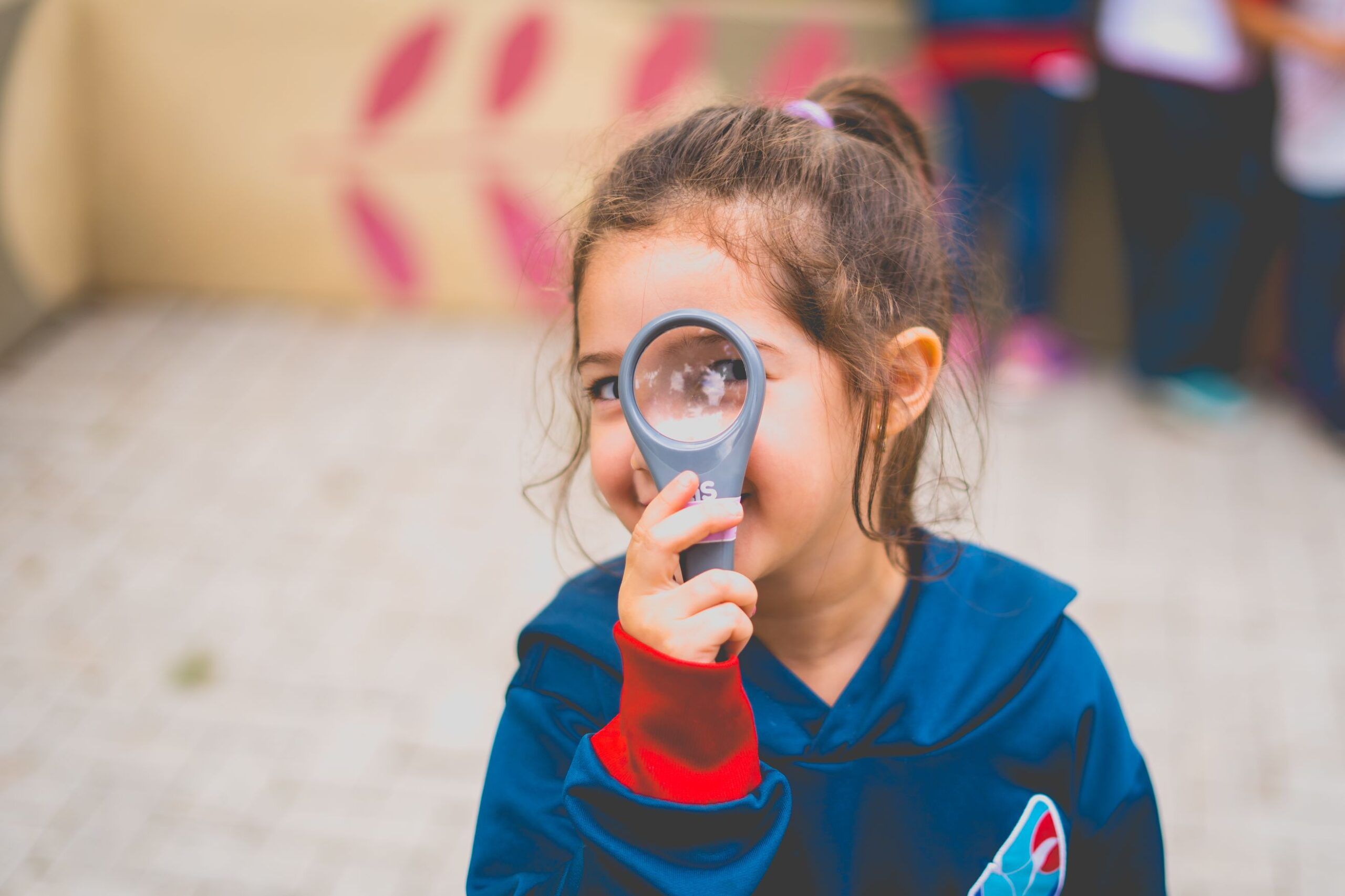 menina no colégio olhando pela lupa